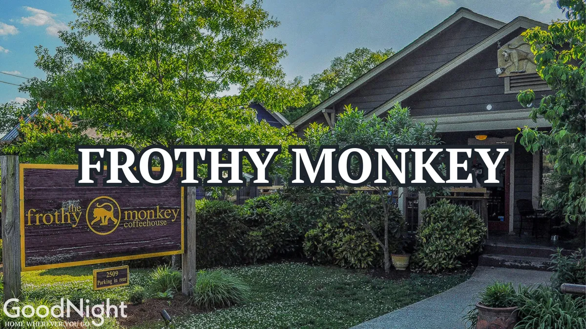 The image showcases the welcoming entrance of Frothy Monkey, surrounded by greenery and inviting steps. The scene conveys a casual, community-focused vibe—perfect for grabbing coffee or working remotely.