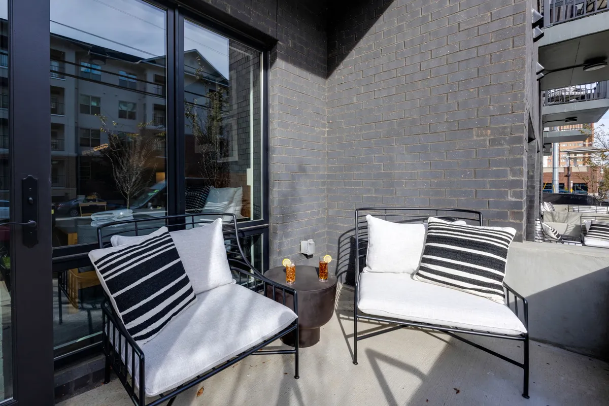 A modern, cozy patio setup with two armchairs and a side table, adorned with decorative items. The space is perfect for enjoying a morning coffee or cocktails with city views as the backdrop.